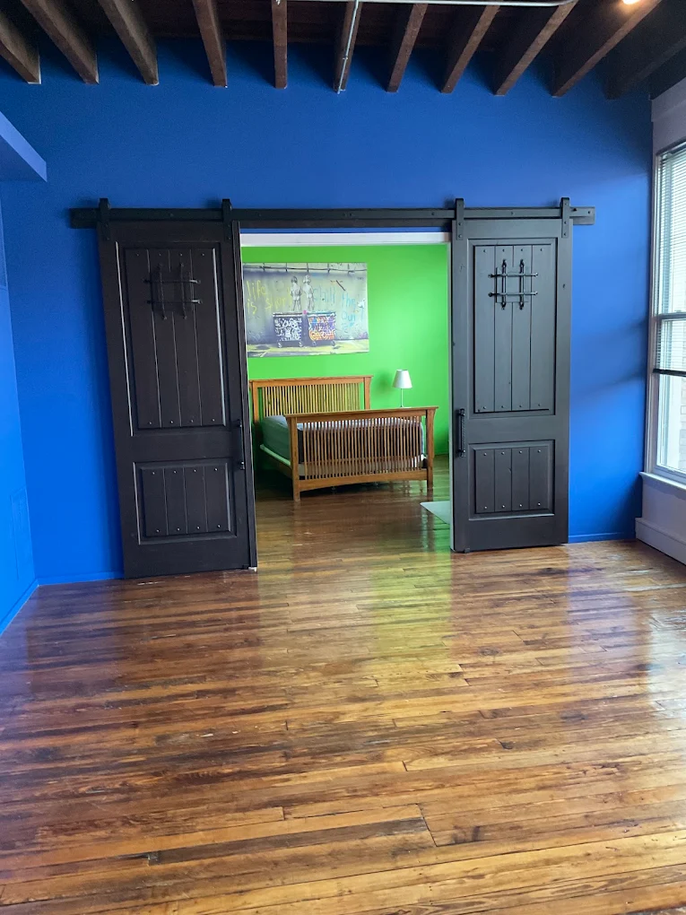 Refinished hardwood floor with black sliding barn doors and a blue wall